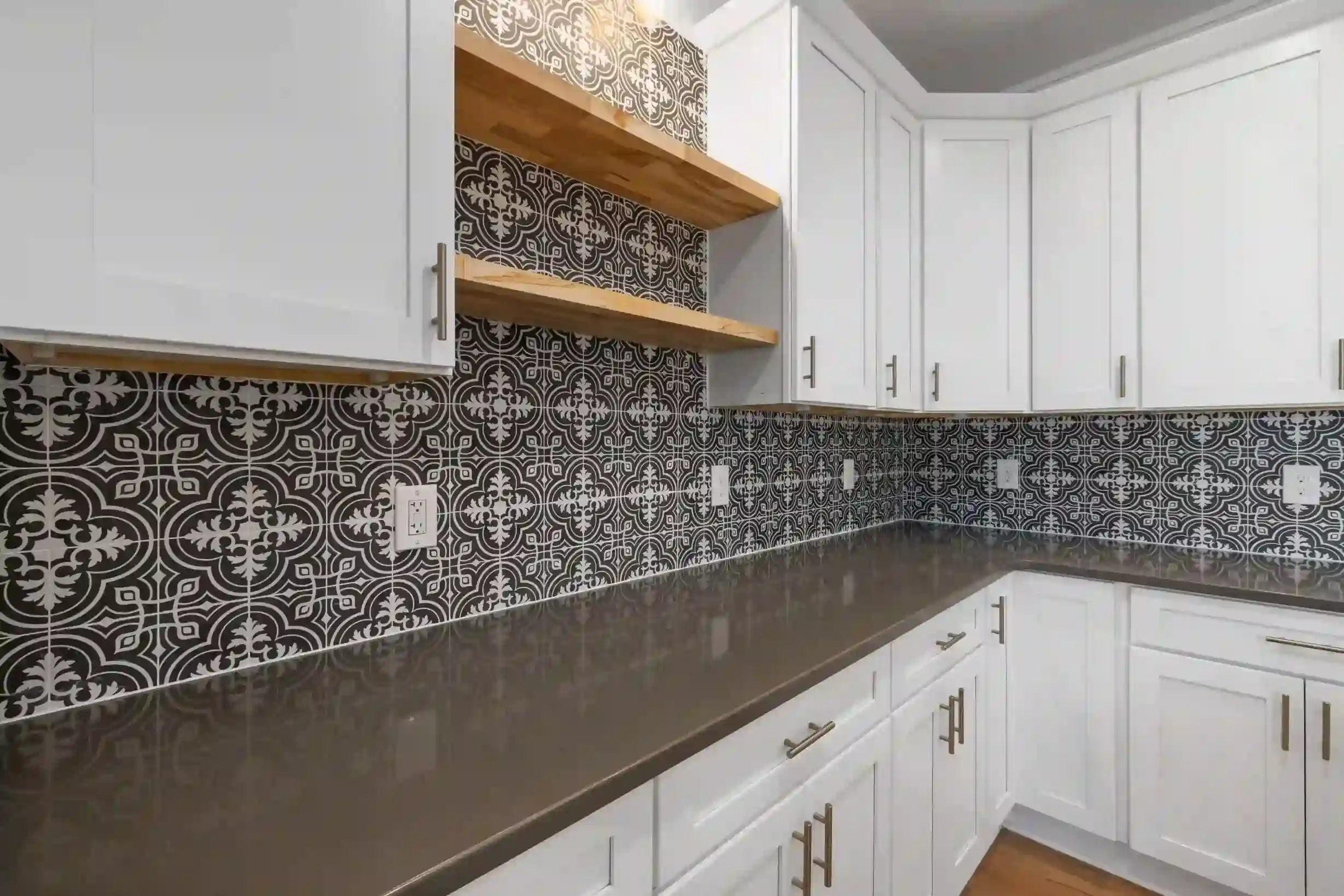 Dark charcoal and white ornate patterned tiles as a kitchen backsplash with white shaker cabinets