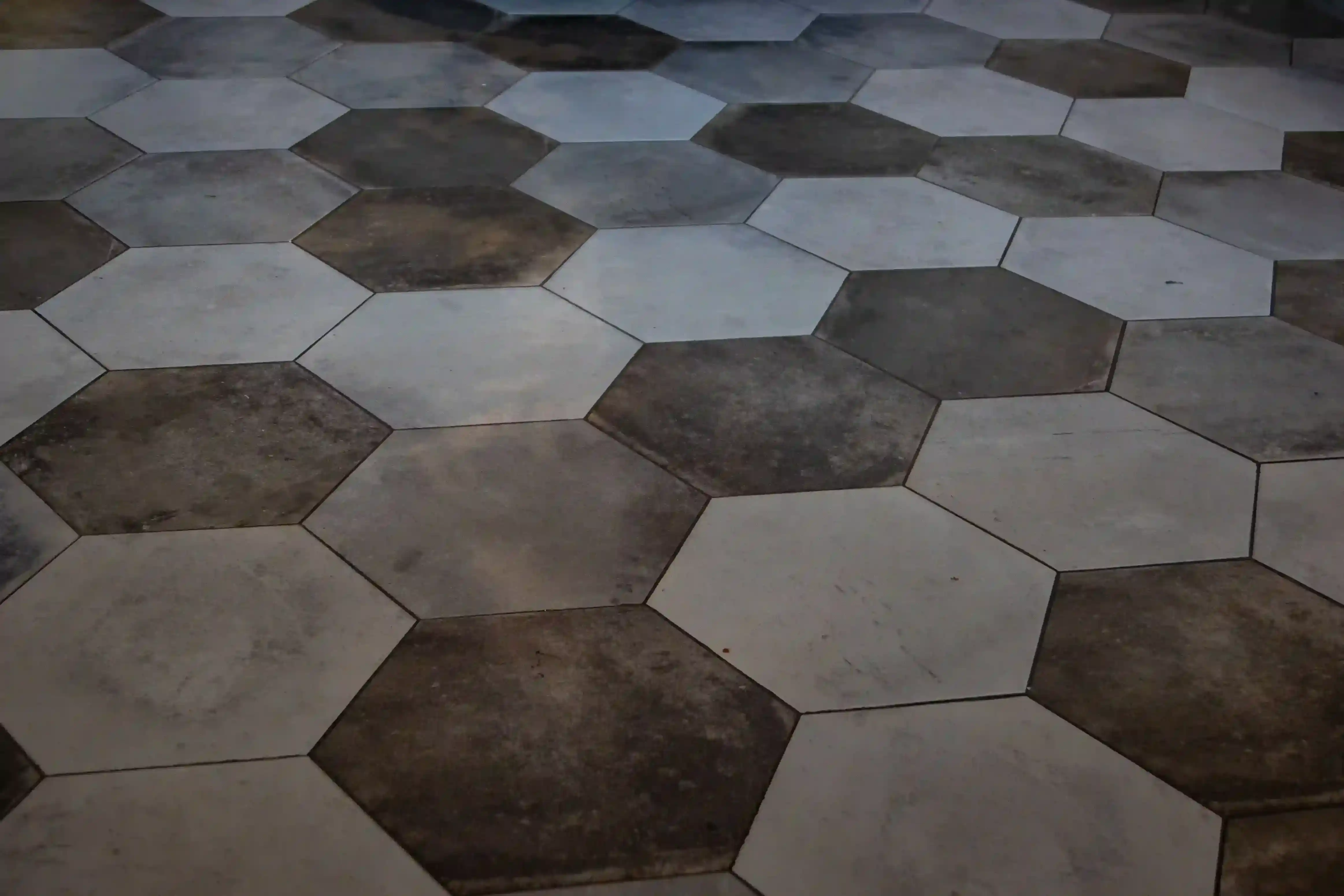 Large-format dark and light gray hexagonal floor tiles in an industrial-style space