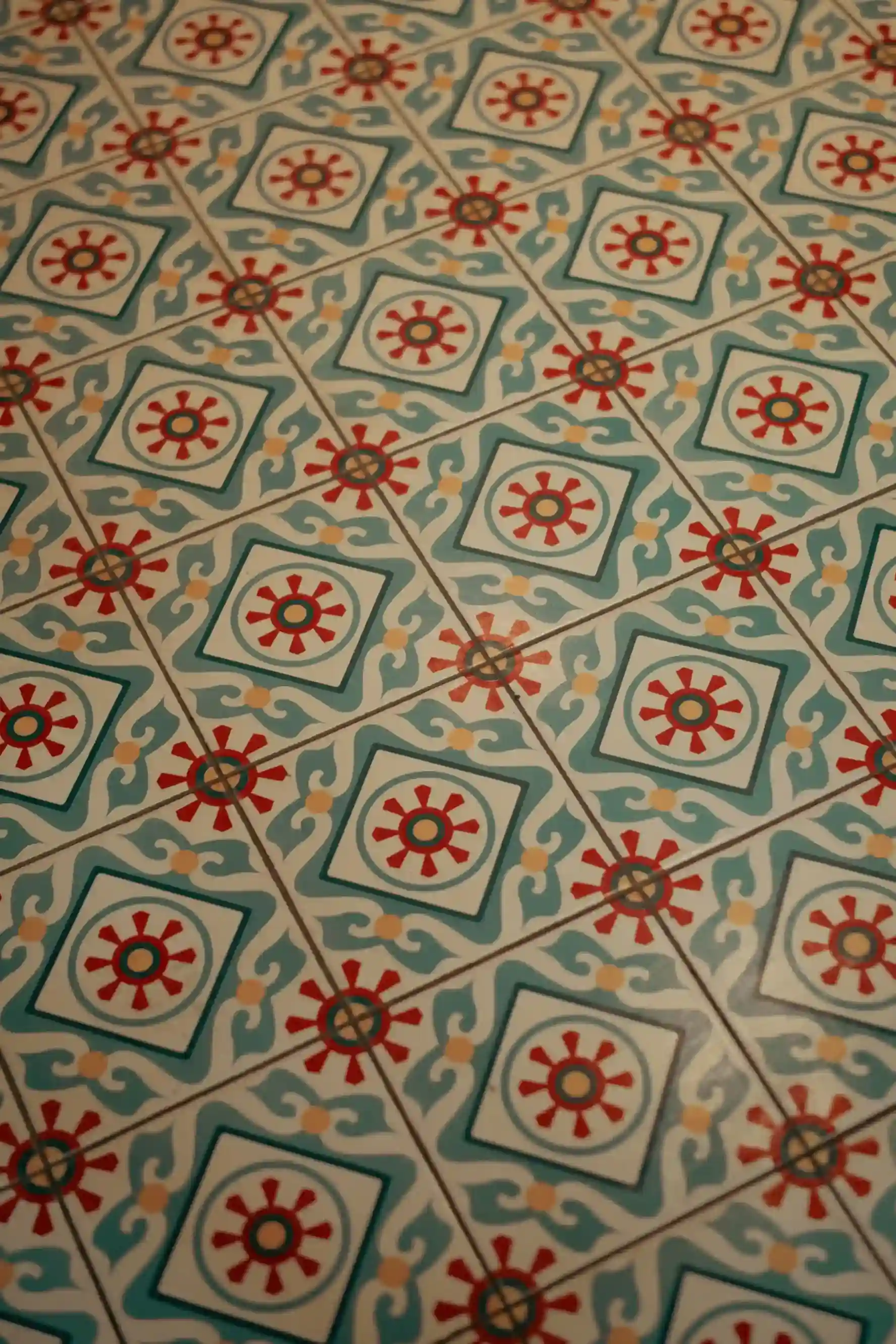 Repeating teal and red medallion pattern encaustic floor tiles installed in a residential space