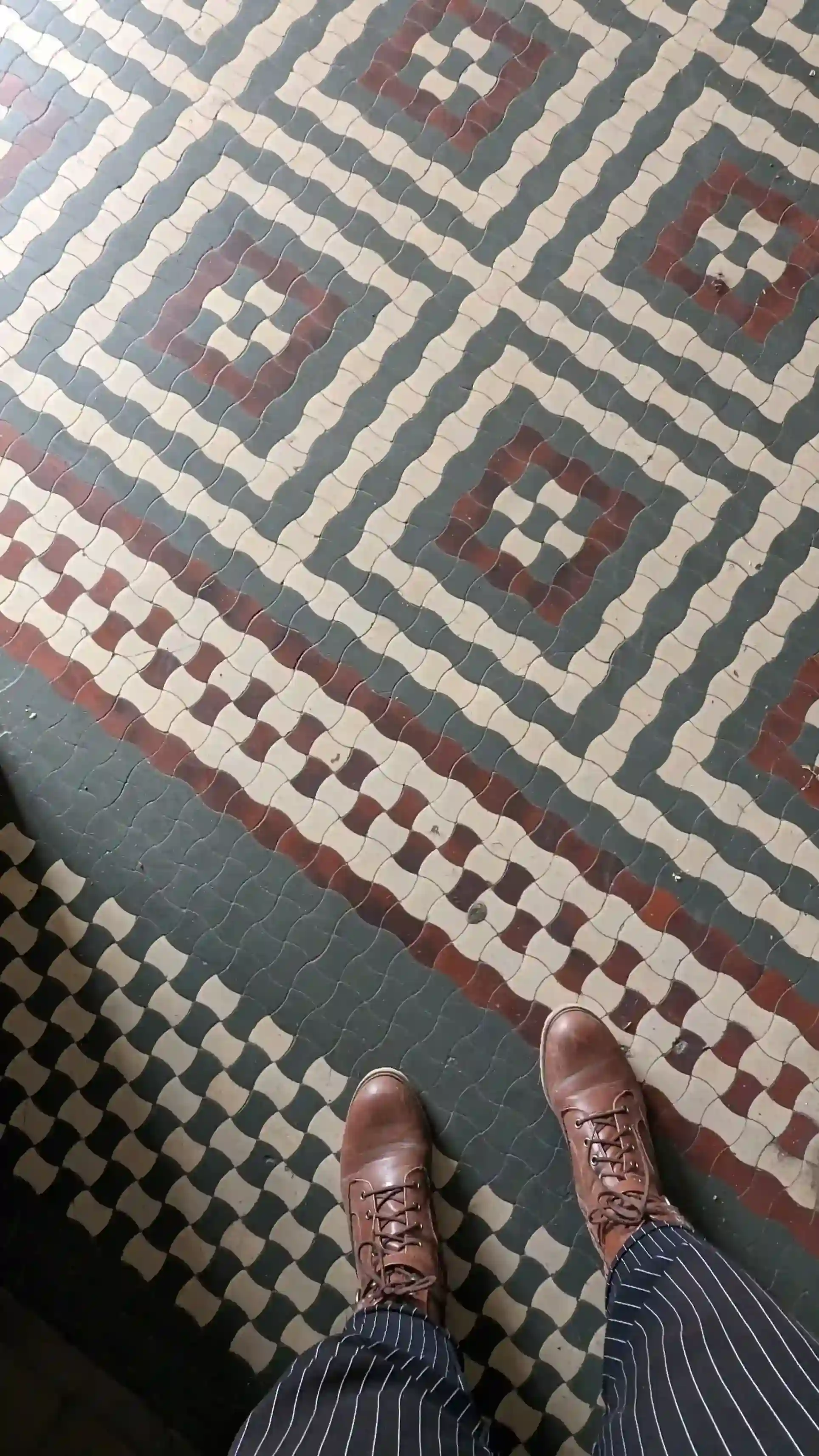 Overhead view of ornate Victorian encaustic floor tiles in green, red, and cream